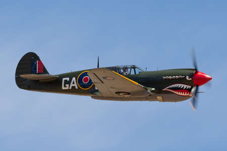 Temora, Australia - November 2, 2013: Curtiss P-40N Kittyhawk World War II fighter aircraft VH-ZOC flying against a blue sky.のeditorial素材
