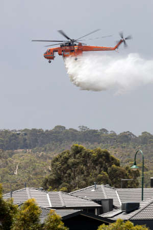 Bundoora, Australia - December 30, 2019: Erickson Air Crane helicopter dropping a large load of water onto a bushfire.のeditorial素材