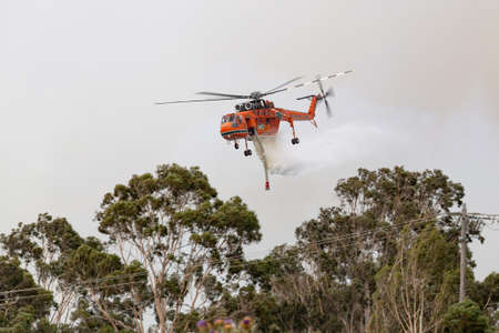 Bundoora, Australia - December 30, 2019: Erickson Air Crane helicopter dropping a large load of water onto a bushfire.のeditorial素材