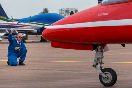 RAF Fairford, Gloucestershire, UK - July 12, 2014: Royal Air Force ground crew member gives directions to the pilot of to a Red Arrows British Aerospace Hawk T.1 jet trainer aircraft as it prepares to taxi to the runway.のeditorial素材