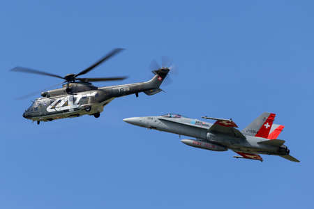 Payerne, Switzerland - August 30, 2014: Swiss Air Force Aerospatiale AS332 (TH89) military utility helicopter T-316 leading a Swiss Air Force McDonnell Douglas F/A-18C Hornet fighter aircraft in formation.のeditorial素材