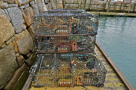 Lobster traps sit on a floating dock along a retaining sea wallの写真素材