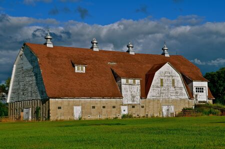 A huge majestic barn stands idle  and is in first stages of exhibiting deterioration.の写真素材