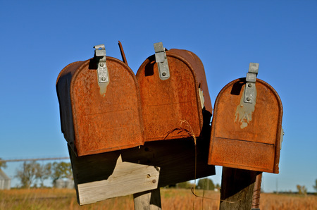 Three old rusty mailboxes in a rural country townの写真素材