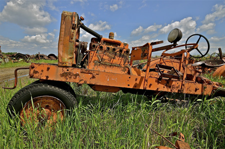 An old tractor with a crank for starting has been stripped of many parts in a junkyard and salvage company.の写真素材
