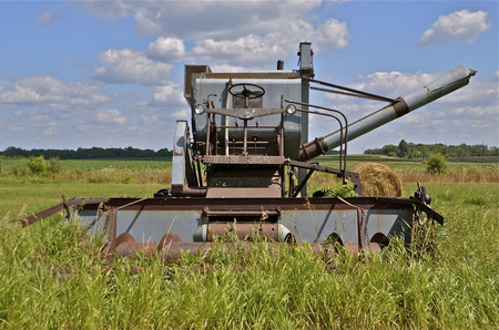 An old self propelled combine sets idle in a field of long grassの写真素材