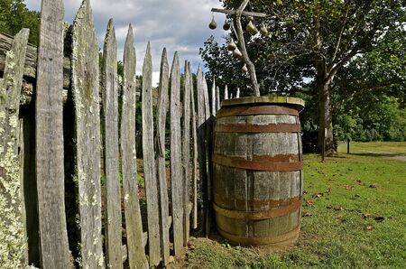 An old wood barrel is left along a weathered fence lineの写真素材