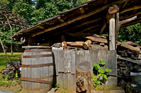 The weathered overhang of of old shed provides a dry storage area for chopped firewood,の写真素材