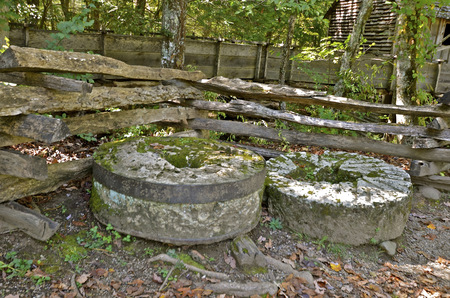 Several millstones along an old weathered wood fence