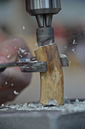 A section of a deer antler held by a plier is having a hole bored through the centerの写真素材