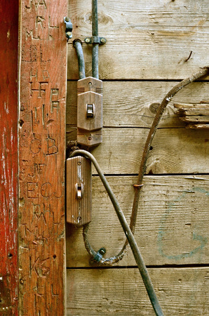 Antiquated electrical wiring in an old barn with carvings on the door frame,