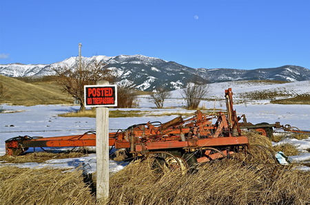 No trespassing sign on a field withe some old machinery standing idle.の写真素材