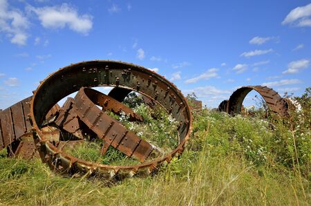 Stack of rims from old tracks and steam engines piled in the weeds and long grassの写真素材