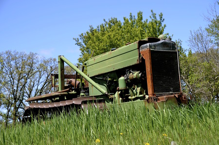 An old bulldozer from years ago is retired and parked in the long grassの写真素材