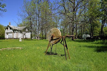 An old antique grindstone is placed in the yard of a rural homestead which is abandoned.の写真素材