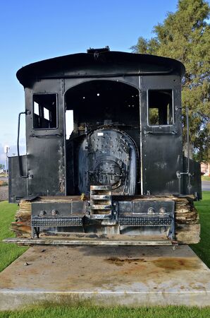 A very old black coal and steam powered locomotive rests on a concrete pad,の写真素材