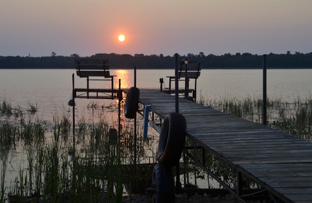 A sunrise reflection on the lake and silhouette  dock create a peaceful settingの写真素材