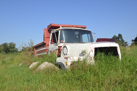 Frame of an truck in a field surrounded by grass and bouldersの写真素材