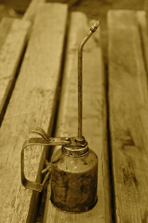 Long stemmed oil can rests on a wood work bench. sepiaの写真素材