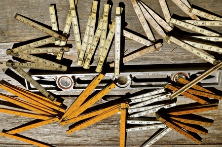 An old metal carpenters level is mixed into a collection of old folding rulers.の写真素材