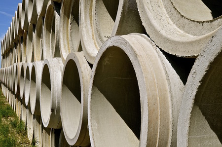 Piles of huge concrete tubes are stacked for engineering industrial projects where water is needed to drainの写真素材
