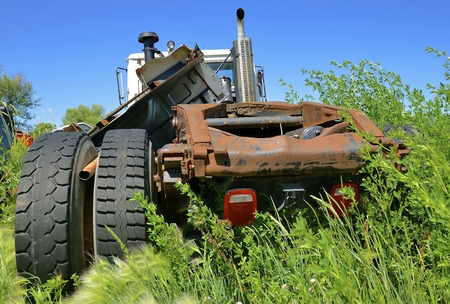 A semi cab is missing the right wheels after a collision and is left in a junkyard.