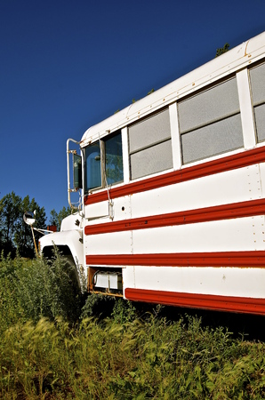 An old school bus painted red and white is converted into a camper