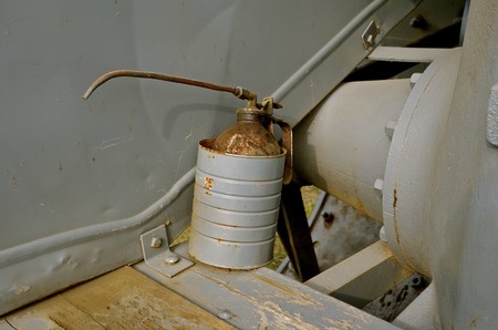 Old gray rusty oil can with a long spout on the platform of a steam engineの写真素材