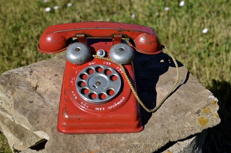 An old toy child's dial telephone left on a rock outside.の写真素材