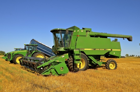 BARNESVILLE, MINNESOTA, August 4, 2016 : The combine and harvest equipment tined up in a wheat field are products of John Deere Co, an American corporation that manufactures agricultural, construction, forestry machinery, diesel engines, and drivetrains.のeditorial素材