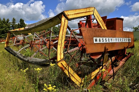 DETROIT LAKES, MINNESOTA, August 5, 2016: The Massey Ferguson name on the self propelled swather with a huge wheel appeared when a merger of Massey Harris and the Ferguson Company farm machinery manufacturer occurred in 1953 and is now owned by AGCO.のeditorial素材