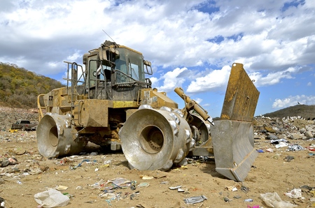 A huge tractor with a front end loader and metal wheels is used to move trash in a city dumpの写真素材