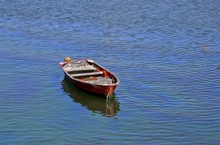 A solitary red fishing boat in the deep blue water.の写真素材
