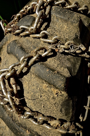 Chains for greater traction in mud, ice, and snow have been placed on the rear tire of a tractorの写真素材