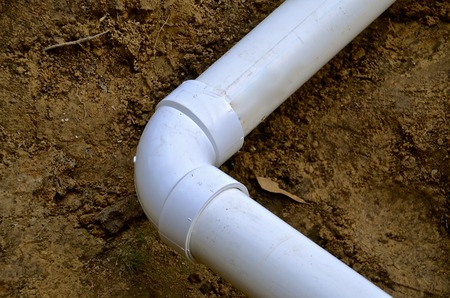 PVC pipe laying in the ground with an elbow for changing directionsの写真素材