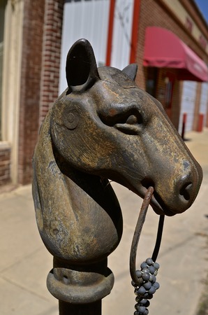 A metal horse head on a post  between sidewalk and cub served as a hitching post and guide for parking.の写真素材
