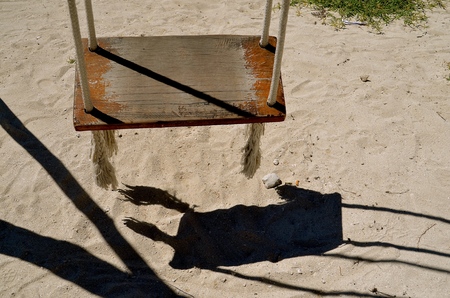 The shadow from a wooden swing is cast upon the fine sandの写真素材