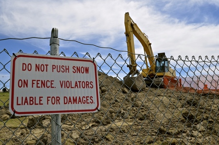 Sign warning of no snow pushed against the construction barrier fence during the summer.の写真素材