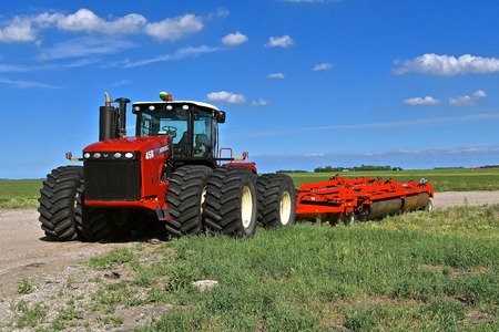 HALSTAD, MINNESOTA, June 5, 2015: The 450 Versatile 4 wheel drive tractor pulling a field cultivator was produced by Versatile  a Canadian brand of agricultural equipment that has also produced augers, swathers, and combine harvesters and now owned by Rosのeditorial素材