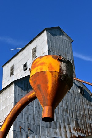 An old grain elevator with a rusty funnel for unloading ground feed or various grains.の写真素材