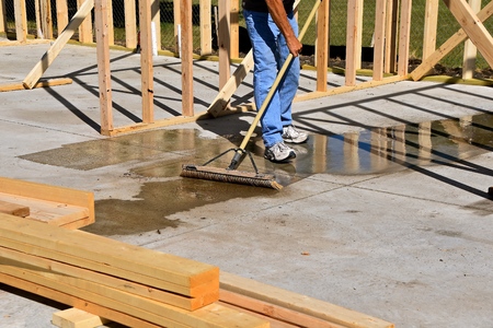 The cement floor of a construction building site is being swept to remove a water puddle after a rain showerの写真素材