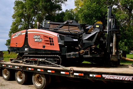 COMSTOCK, MINNESOTA, August 21, 2017 iThe tractor trencher loaded on a flatbed trailer  is a Ditch Witch, a trade name of Charles Machine Works, an American brand of underground utility construction equipment, which has been in operation since 1949 from Pのeditorial素材