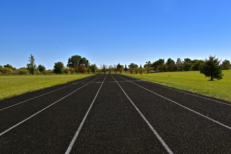 A five lane rubber track appears to run into the distant treesの写真素材