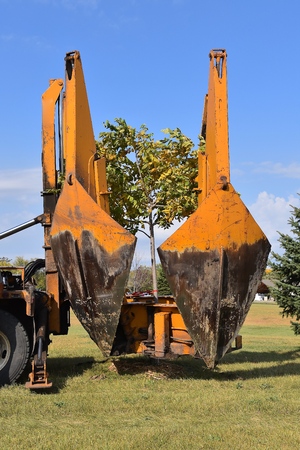 The mounted spade, jaws, and bucket are part of a tree removal machine  which removes and transplant...