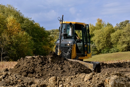 A bulldozer is pushing earth at a rural construction site.