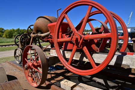 Red painted huge fly wheel of a gas engine which operated a cement mixer on wheelsの写真素材