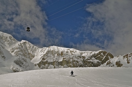 A tram travels over a solitary downhill skier.の写真素材
