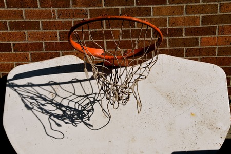The net of a basketball hoop is shadowed against the white backboard which tis hung upside down.の写真素材