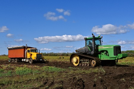 OSAGE, MINNESOTA, Sept 26, 2017: The 9620 T tractor pulling a truck stuck in mud is a product of John Deere Co, an American corporation that manufactures agricultural, construction, forestry equipment, machinery, and diesel engines,のeditorial素材