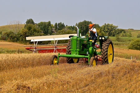 ROLLAG, MINNESOTA, Sept 2, 2017: Unidentified operator of a  tractor and swather provide a field demonstration at the annual WCSTR farm show in Rollag held each Labor Day weekend where 1000's attend.のeditorial素材